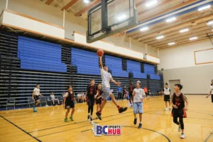 Showtime Academy's athlete takes an open layup while his team and G2 Athletics players watch.