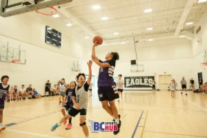 Fundamentals Basketball player jumps up for a shot over a JR Basketball athlete.