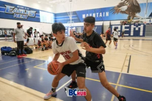 A Drive Basketball athlete holds the ball at his end of the court, while a player from Venom Sports Academy closely guards him.
